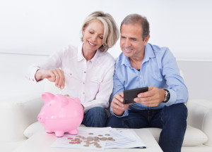 Mature Couple Calculating Coin In The Piggybank